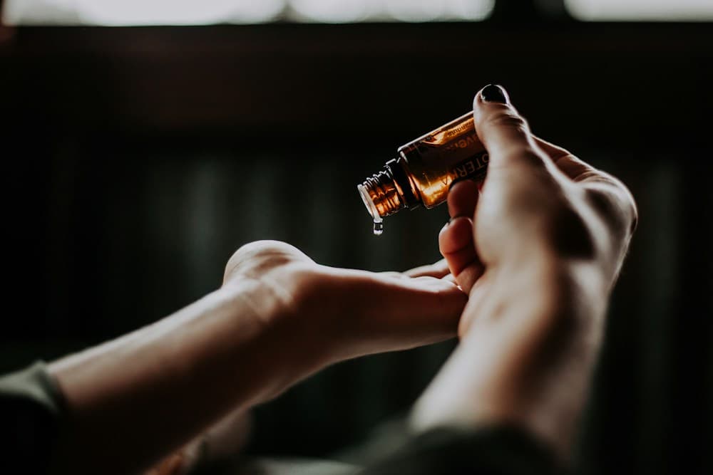 A drop of aromatic oil being poured into a hand, illustrative photography